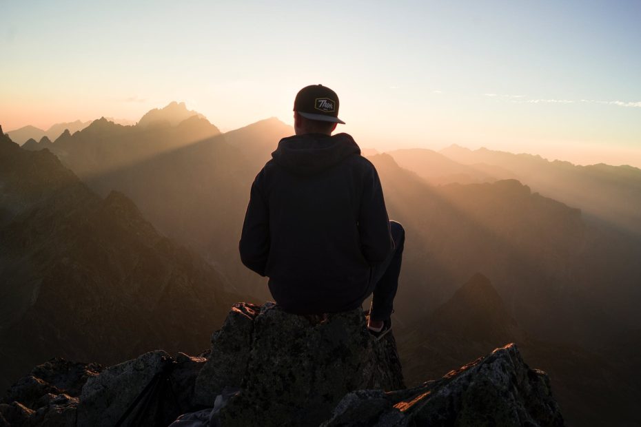 man sitting on the mountain edge